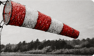 A red and white windsock on a grass airfield